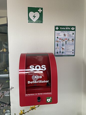 AED im roten Wandkasten rechts an der Wand