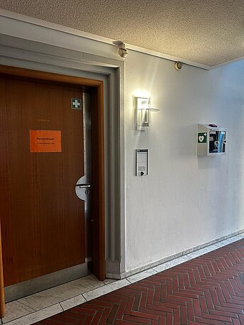 AED im weißen Wandkasten rechts neben der Tür zu Raum 142, Abteilung Standesamt AED im weißen Wandkasten rechts neben der Tür zu Raum 142, Abteilung Standesamt