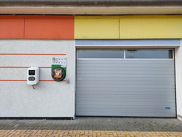 Öffentlicher AED im runden Wandkasten direkt links neben dem Rolltor Öffentlicher AED im runden Wandkasten direkt links neben dem Rolltor