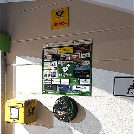 Öffentlicher AED im runden beleuchteten Wandkasten rechts neben dem Eingang beim Briefkasten