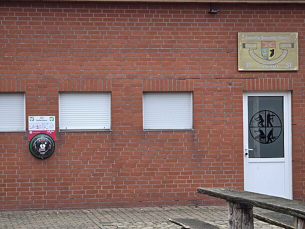 AED im runden, beleuchteten Wandkasten links neben der Eingangstür zum Feuerwehrhaus Heemsen