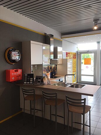 AED wandmontiert an der Wand rechts neben dem Durchgang zu den Toiletten