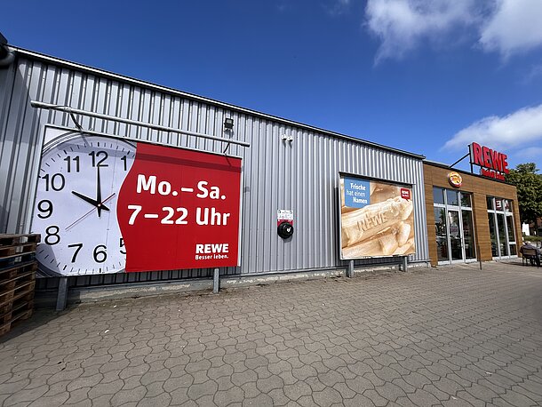Öffentlicher AED an der linken Gebäudeseite (Zufahrt Weidendamm) zwischen den Großflächenwerbungen hinter Bäckerei Bertermann