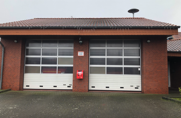 Öffentlicher AED zwischen den Toren am Feuerwehrhaus im roten Wandkasten.