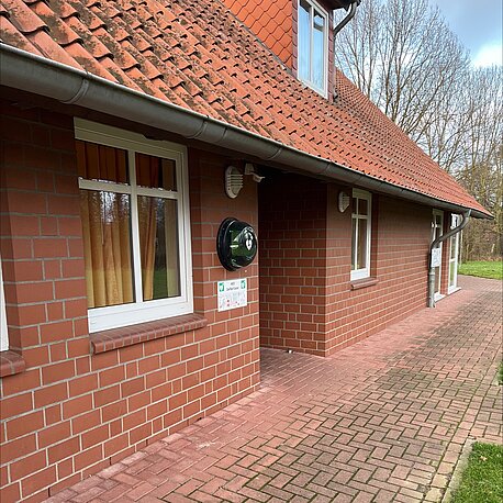 Links neben dem Eingang zum Feuerwehrgerätehaus im runden Wandkasten