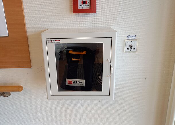 AED an der Wand auf der rechten Seite direkt hinter der Eingangstür AED an der Wand auf der rechten Seite direkt hinter der Eingangstür