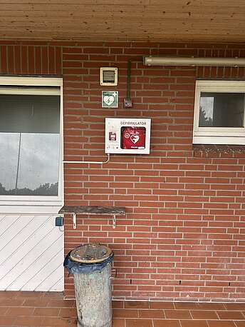 AED im weißen Wandkasten zwischen den Türen zu den Umkleiden