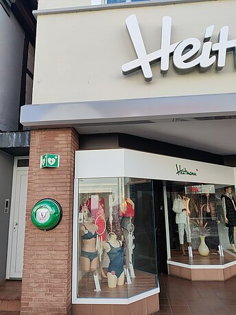 AED links neben dem Schaufenster an der Wand