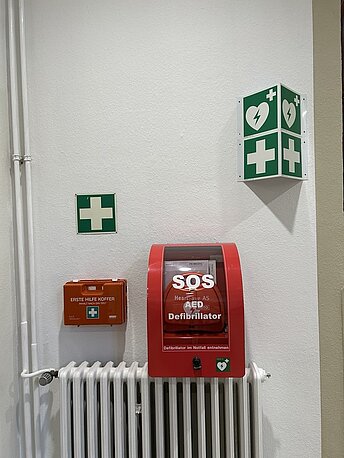 AED gleich rechts an der Wand über der Heizung im roten Wandkasten AED gleich rechts an der Wand über der Heizung im roten Wandkasten