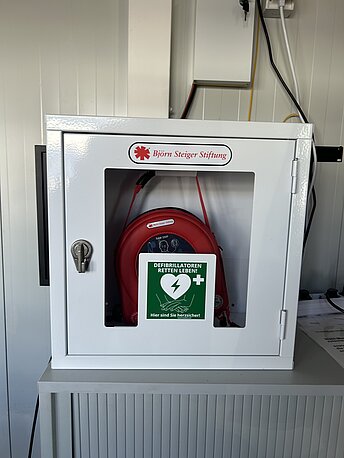 AED im weißen Wandkasten an der Wand hinter der Tür AED im weißen Wandkasten an der Wand hinter der Tür