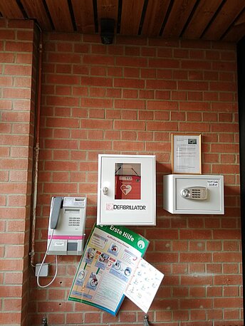 Der AED befindet sich neben dem Münztelefon