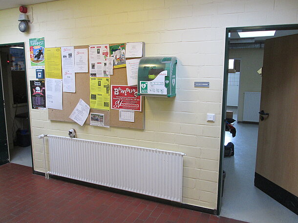 Der Defi hängt zwischen den Umkleiden neben der Pinnwand