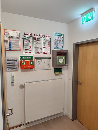 AED im grünen Wandkasten über der Heizung