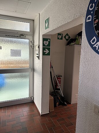 Ausschilderung zum AED am Durchbruch folgen.