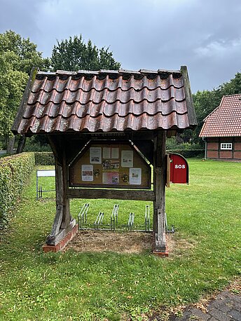 Öffentlicher AED im roten Kasten an der Stirnseite der Infotafel links an der Einfahrt zum Heimathaus Wechold
