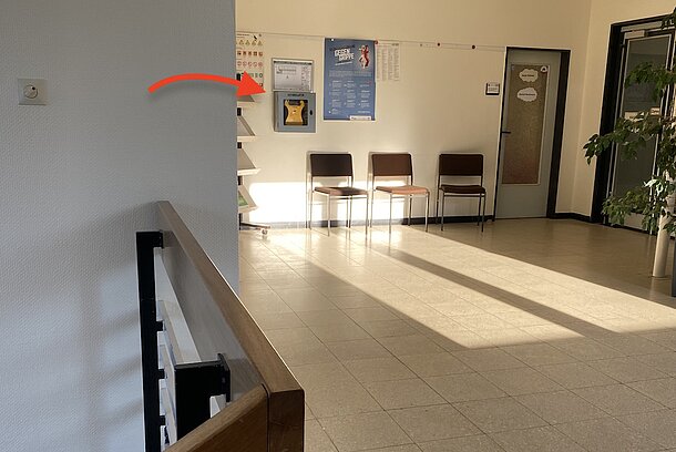 Flur im ersten Obergeschoss, AED im Wandkasten auf der Wand über dem Wartebereich neben der Tür zu Zimmer 102 Flur im ersten Obergeschoss, AED im Wandkasten auf der Wand über dem Wartebereich neben der Tür zu Zimmer 102
