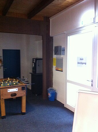 Rechts neben der Treppe. Neben der Tür zum Studio 3 im Erste Hilfe AEd Kasten