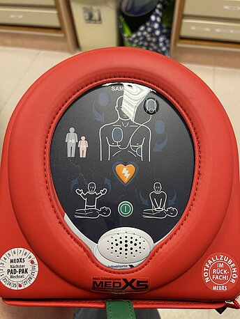 AED in roter Schutzverpackung in den Mitarbeiterräumen. Bitte in der Apotheke fragen. AED in roter Schutzverpackung in den Mitarbeiterräumen. Bitte in der Apotheke fragen.