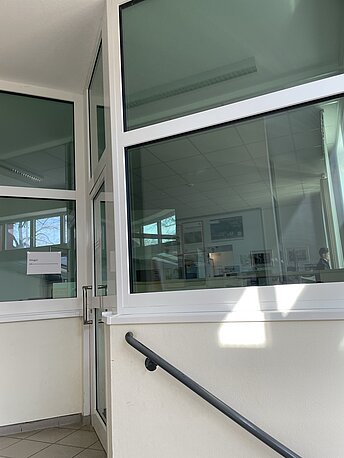 Im Treppenhaus durch die Glastür in den Empfangsbereich.