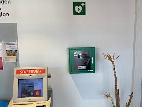 AED im grünen wandmontierten Kasten neben dem Auszugsterminal AED im grünen wandmontierten Kasten neben dem Auszugsterminal